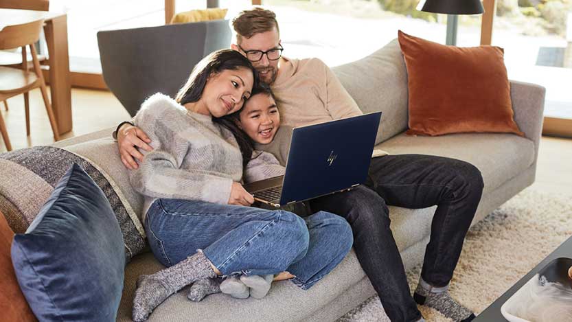 A family relaxing on the sofa and looking at a laptop