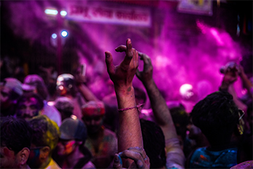 A group of people raise their hands while celebrating in a color festival.