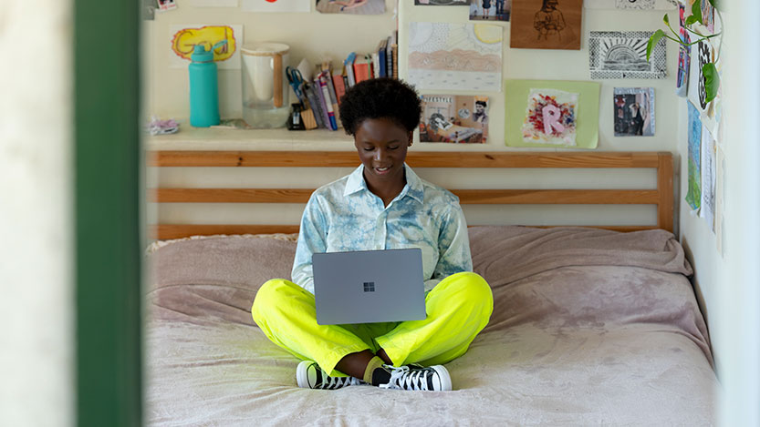 A teenager working with her laptop in her bedroom.