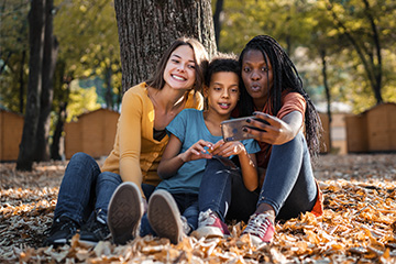 Three youngsters outdoors, taking a picture of themselves with a mobile