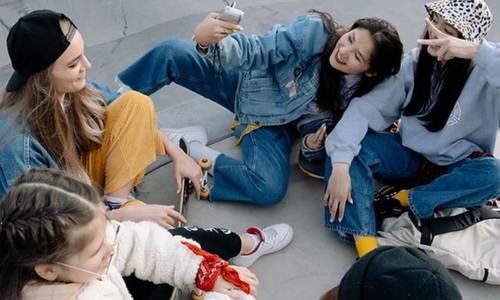 Group of young women and girls at a skate park laughing and taking pictures together.