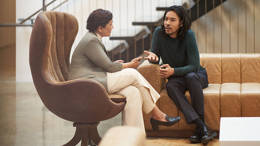 A man and a woman talk to each other while sitting in a lounge.