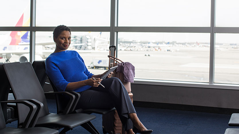 A businesswoman waits to board her flight while working on her tablet.