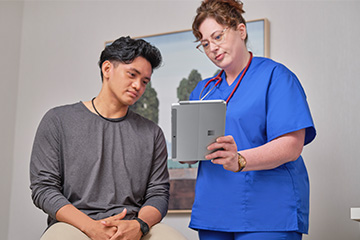 A doctor shows a patient results on a tablet.