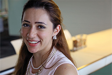 A young smiling woman in an office background.