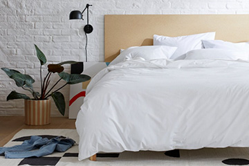 A bed with white linen and a wooden headboard and frame