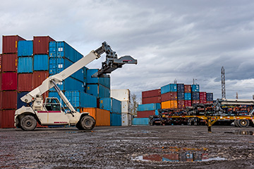 View of a crane outdoors surrounded by containers.