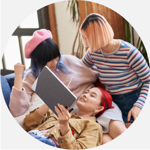 Three people hugging and talking while one of them holds a tablet and pen at home.