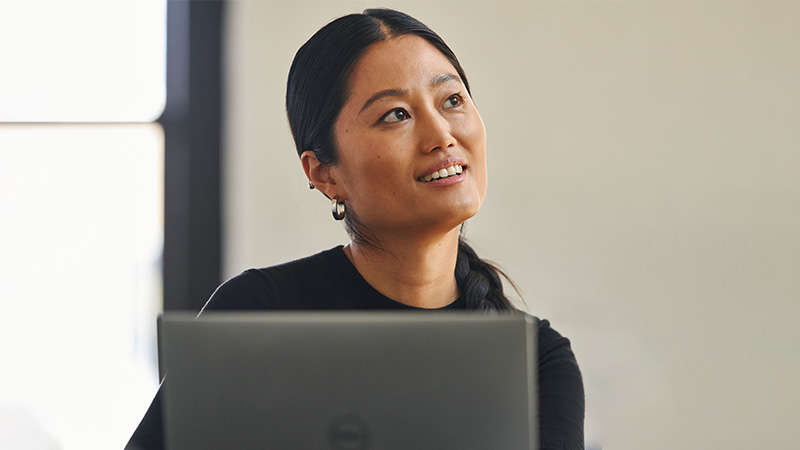A woman sitting behind a computer and looking away from the camera.