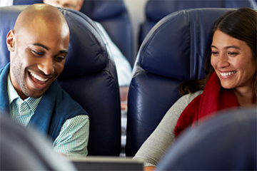Two smiling people sitting next to each other on an airplane.