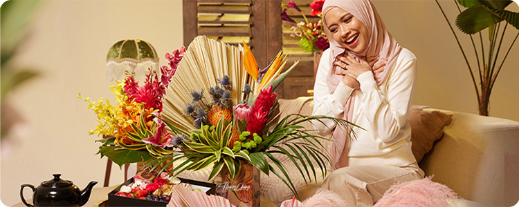 Person sitting in front of a big bouquet of flowers and smiling.